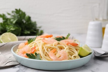 Tasty spaghetti with shrimps, lime and parsley on white marble table, closeup