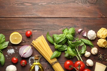 Different types of pasta, spices and products on wooden table, flat lay. Space for text
