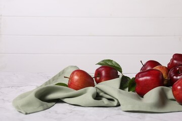 Fresh ripe red apples with leaves on white marble table. Space for text