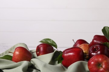 Fresh ripe red apples with leaves on table near white wall