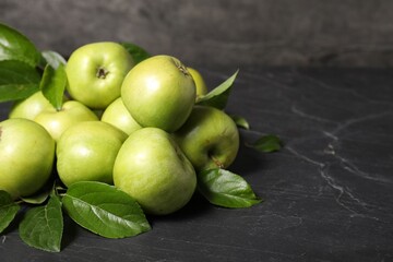 Ripe green apples with leaves on dark grey table. Space for text