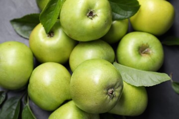 Ripe green apples with leaves on dark grey table, closeup