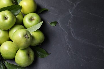 Ripe green apples with leaves on dark grey table, flat lay. Space for text