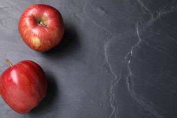 Ripe red apples on black textured table, flat lay. Space for text