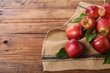 Ripe red apples with leaves on wooden table. Space for text