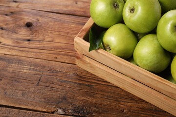 Fresh ripe green apples in crate on wooden table. Space for text
