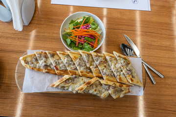Turkish pita with minced meat. Turkish pizza with minced meat pide and a bowl of salad on a brown...