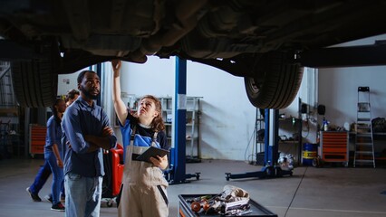 Licensed technician in repair shop showing customer what needs to be changed on his car. Garage...