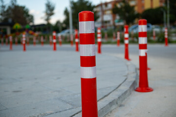 Orange traffic cone, parking is prohibited. Plastic red barrier. Row of red and white traffic barrier pole on road. A barrier made of plastic columns with reflective pigment on an asphalt road.