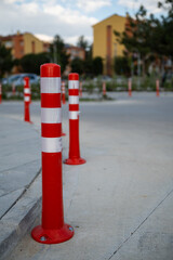 Orange traffic cone, parking is prohibited. Plastic red barrier. Row of red and white traffic barrier pole on road. A barrier made of plastic columns with reflective pigment on an asphalt road. 