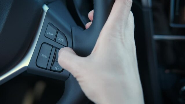 Girl press button of automotive technology in car. A view of female use the buttons of her steering wheel. A concept of new technology and modern car.