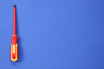 Screwdriver with red handle on blue background, top view. Space for text
