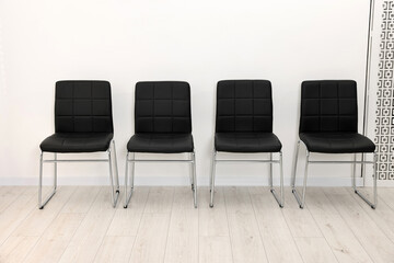 Many chairs near white wall in waiting area indoors