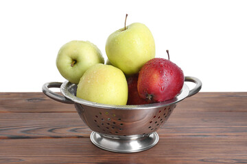Metal colander with fresh apples on wooden table against white background