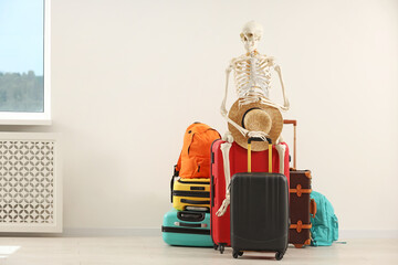 Waiting concept. Human skeleton with hat and suitcases indoors, space for text