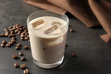 Coffee cream liqueur in glass and beans on grey table, space for text