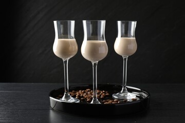 Coffee cream liqueur in glasses and beans on black wooden table
