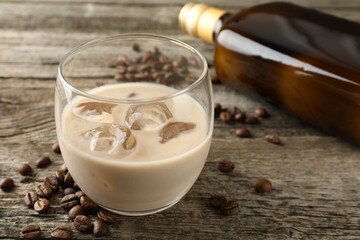 Coffee cream liqueur in glass, beans and bottle on wooden table, closeup