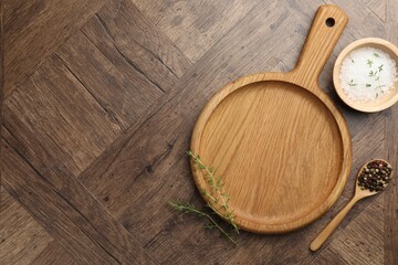 Cutting board and different spices on wooden table, flat lay. Space for text