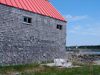 Weathered Clapboard warehouse sits on the docks on the Lubec Narrows between the US and the...