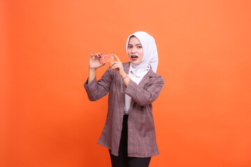 Young indonesia woman hijab suit shocked both hands showing isolated plastic debit credit card on...