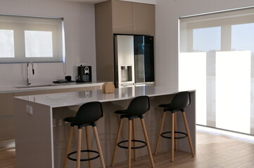 part of big beige kitchen with table with high black wood chairs