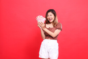 indonesia woman's expression is cheerful, happy, candid, both hands holding rupiah money, wearing a...