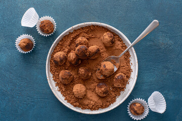 Artisanal chocolate truffles dusted with cocoa powder on a plate with a spoon