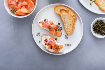 Making bruschetta with cream cheese, smoked salmon with toast and capers