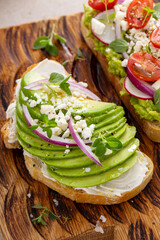 Fresh avocado toasts on wooden board