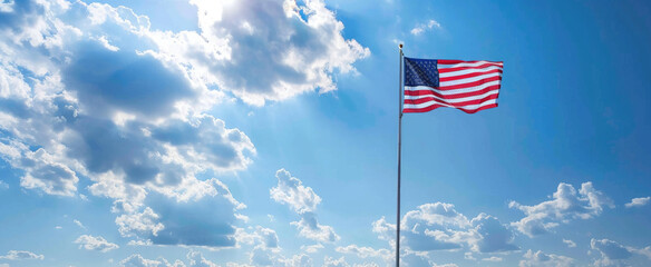American flag blowing in the wind with a partly cloudy blue sky, USA