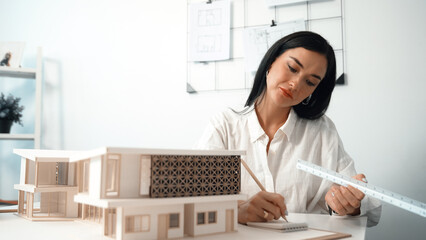 Closeup image of young architect engineer writing house structure in blueprint with document and...