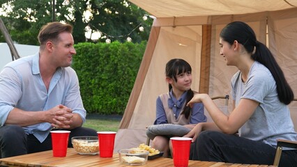 Family all together sit at camp in garden with tasty snack. Lovely parent use outdoor camping...