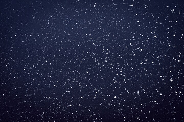 Natural snow particles in the air. Dark blue fading to black background. High quality photo