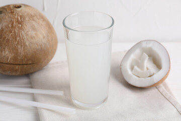 Glass of coconut water and nuts on white table