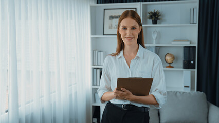 Friendly psychologist woman in clinic office professional portrait with smile and holding clipboard...