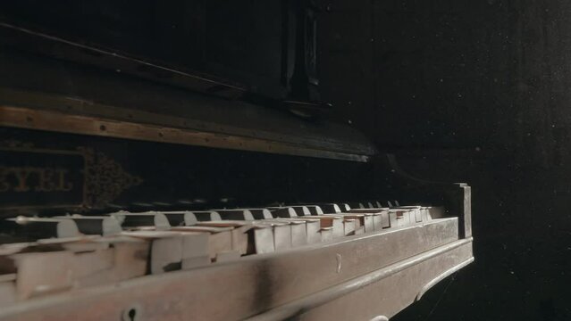 Broken and abandoned old wall piano with dust particles in the air at the music room of an abandoned house (Travelling camera, slow motion, ProRes 422 HQ, 4K)