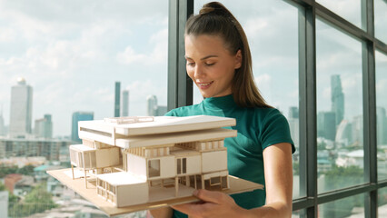 Young smart architect engineer holds architectural model while inspect house model. Professional...