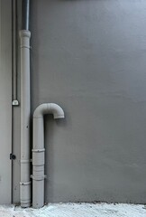 Gray Concrete Wall with Polyvinyl Chloride PVC Sewer Pipe Installation