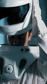 Man takes off the astronaut's helmet, disconnects from the suit. A young attractive male astronaut is on a space exploration mission on an orbital station. Vertical Shot.