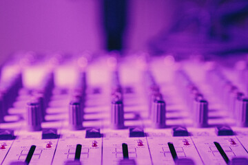A purple background with a white and sound board with many knobs