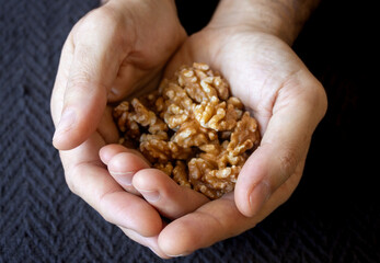 Hands of a young man holding a handful of walnuts.Close up photo