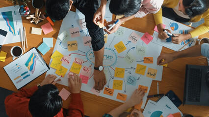 Group of business people writing sticky note and making mind map to brainstorming marketing idea at meeting. Top aerial view of investors sharing plan or strategy and stick note at paper. Convocation.