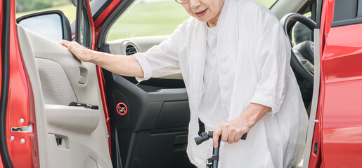 杖をついて車の助手席から降りるシニア・高齢者女性
