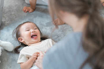 お着替えをする女の子・幼児と母親・ママ・女性保育士
