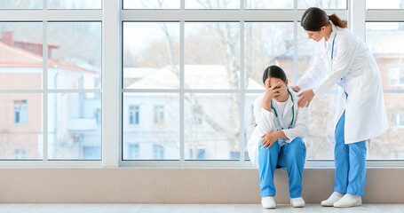 Obraz premium Female Asian doctor calming her colleague in hall of clinic