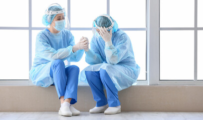 Female Asian surgeon calming her colleague in clinic