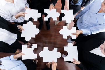 Top view multiethnic business people holding jigsaw pieces and merge them together as effective...