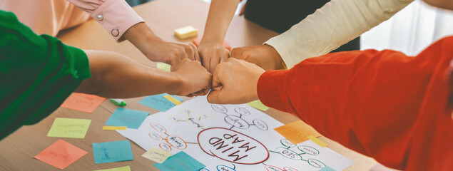 Young happy creative startup group join circle fist bump hands together surrounded by marketing...