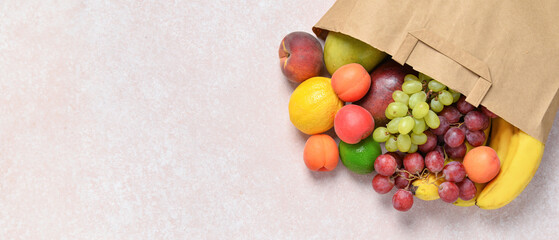 Paper bag with fresh fruits on grey background
